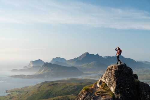 Turgåer på toppen av fjell i Nord-Norge som ser utover sjø og fjell.