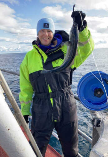 Janne holder opp en stor fisk på fiskebåt i Lofoten.
