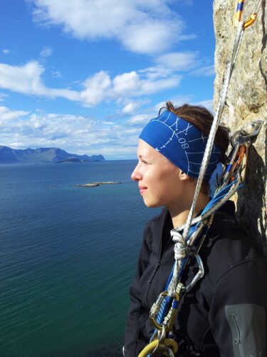 Sarah i fjellvegg med klatreutstyr og utsikt.