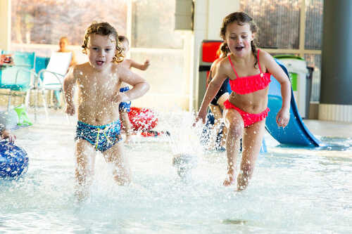 To glade barn som løper i basseng.