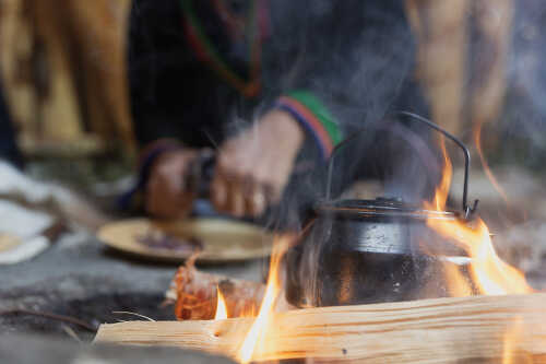 Kaffe på bålet med samisk drak i bakgrunnen