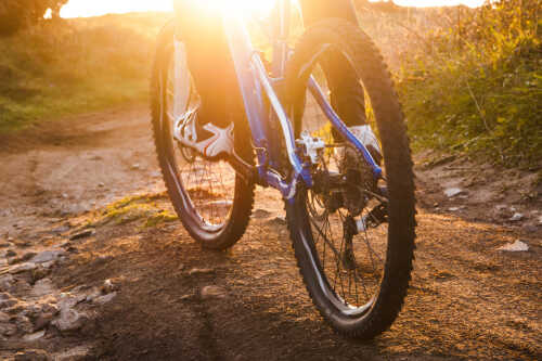 Nærbilde av to sykkelhjul på tur i solnedgang